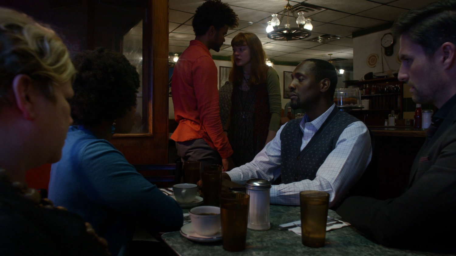 Robyn confronting Malcolm and other Kilgrave's anonymous members meeting in Broadway Restaurant at night.
