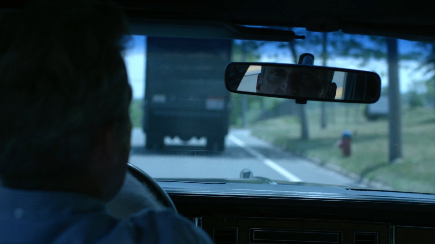The Jones family in a car following behind a truck.