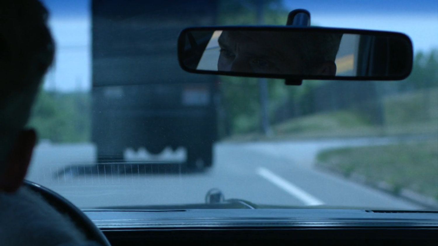 The Jones family in a car following behind a truck.