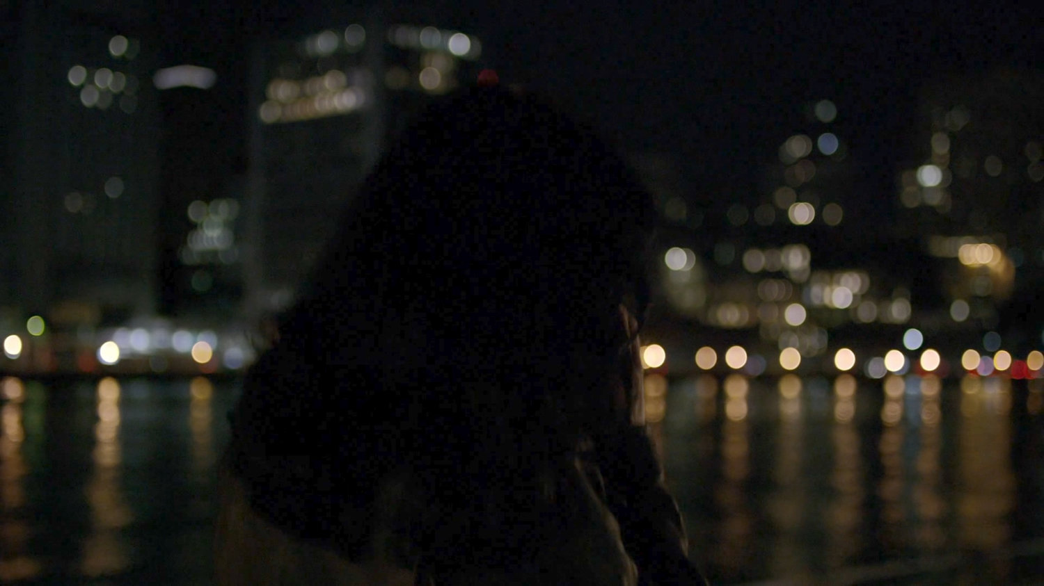 Jessica on phone by river at night.