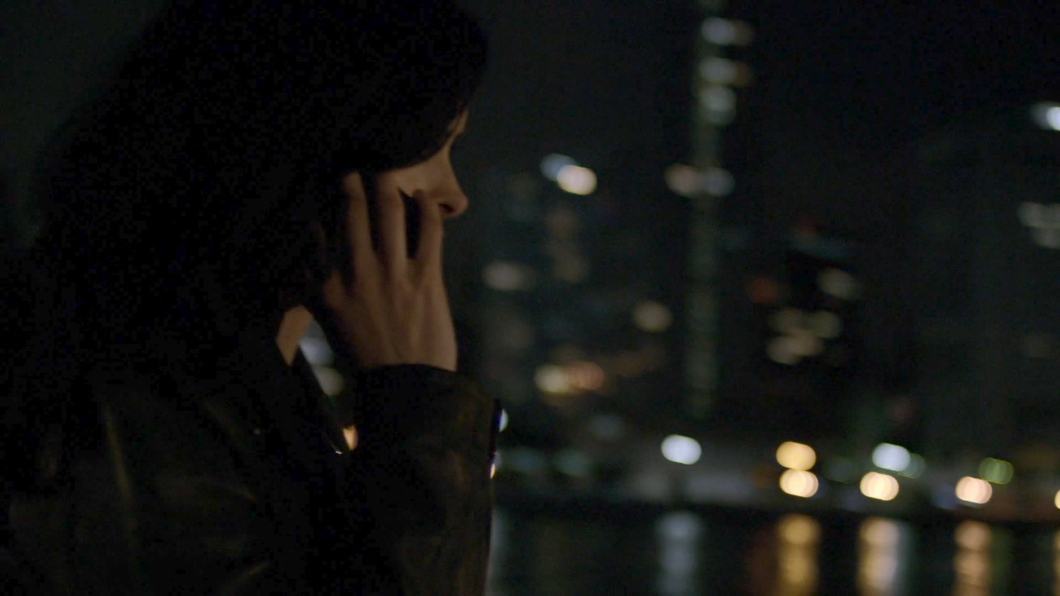 Jessica on phone by river at night.