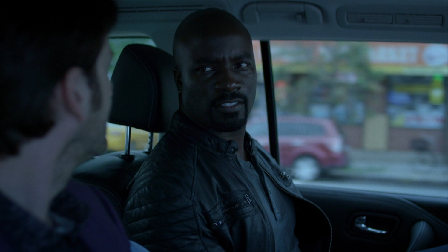 Luke and Kilgrave on back seat of car.