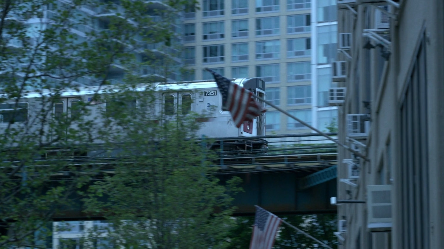 Elevated train traveling behind trees and Zalk Chemical Technologies building