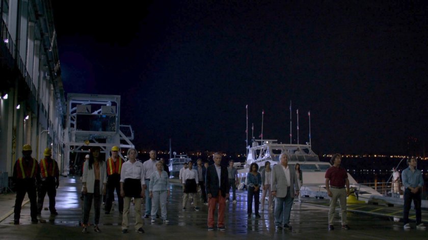 A large group of civilians under Kilgrave's sway stand on the Hudson Ferry Terminal dock.