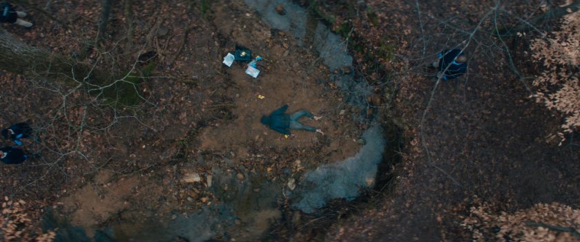 Aerial of Agnes and Herb looking at body near stream in New Jersey woods.