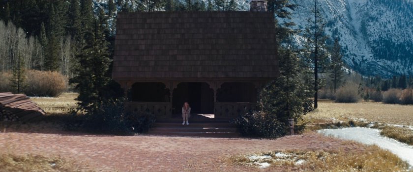 Wanda on the steps of a cabin by an alpine lake.