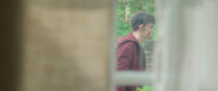 Billy walks past a window outside his house.
