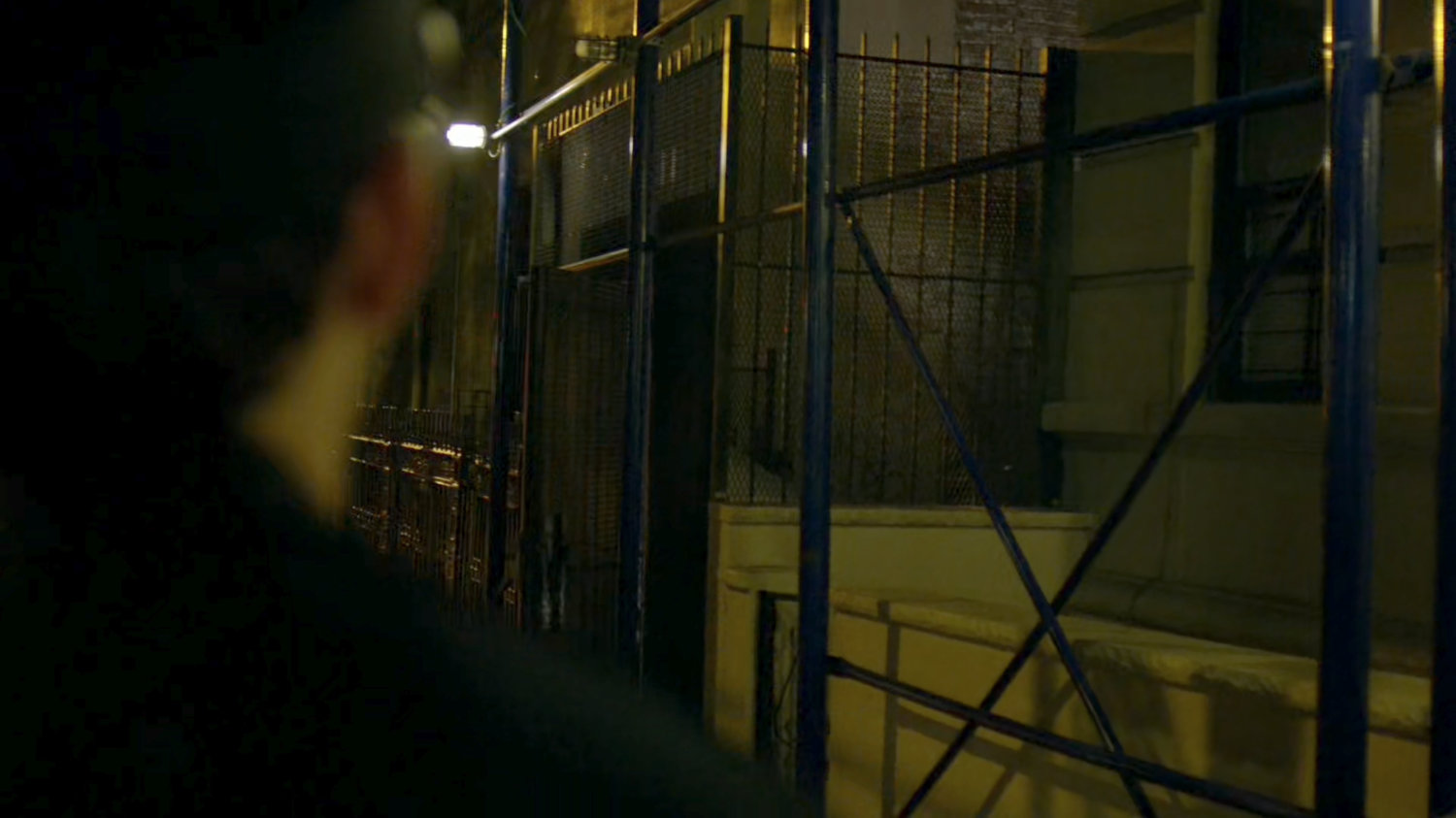 Police officer looking warily into an alley.