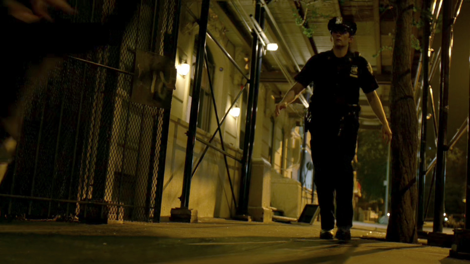 Police officer looking warily into an alley.