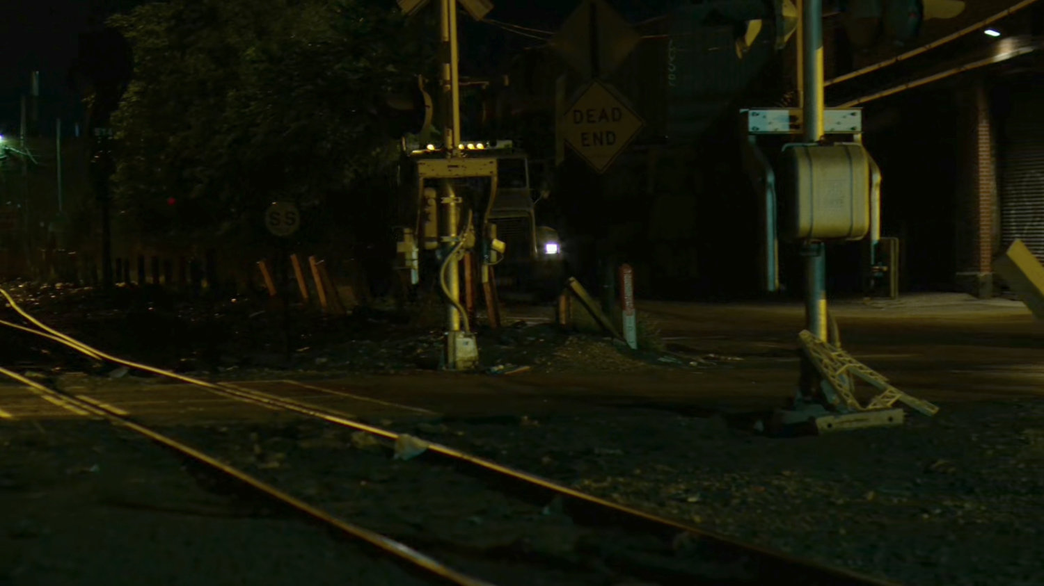 Truck approaches railroad tracks at night.