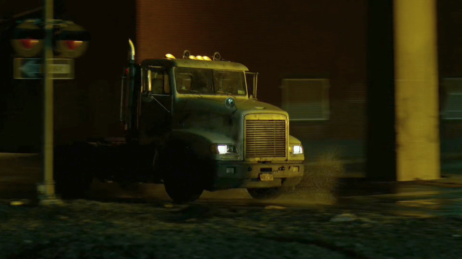 Truck speeds past railroad tracks at night.