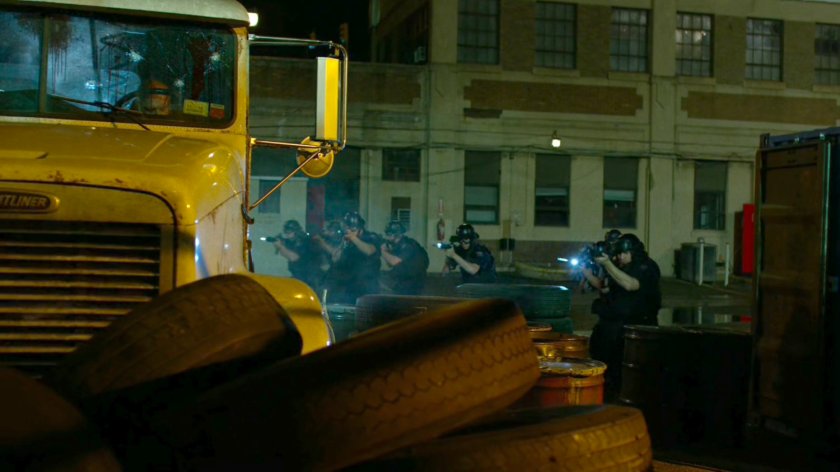 Police approach semi trailer outside refinery at night.