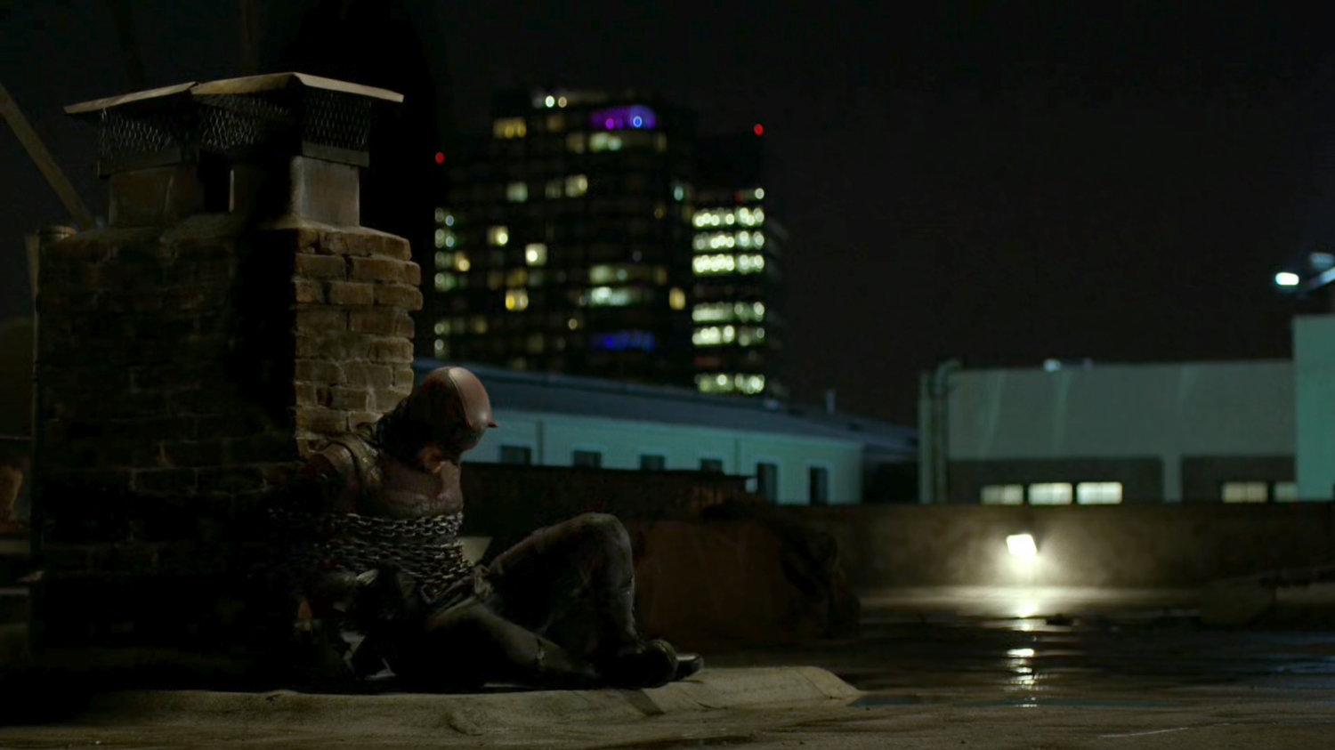Daredevil chained to a brick smokestack.