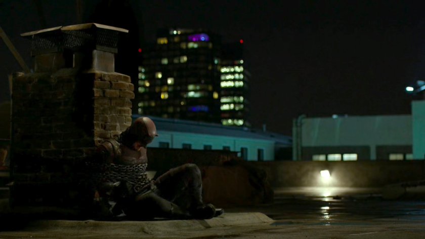 Daredevil chained to a brick smokestack.