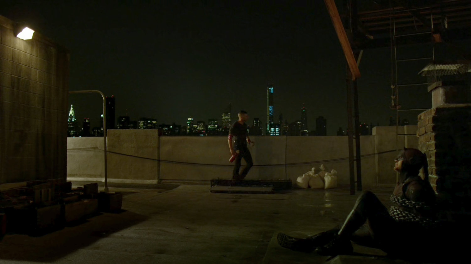 Frank with a chained up Daredevil on rooftop.
