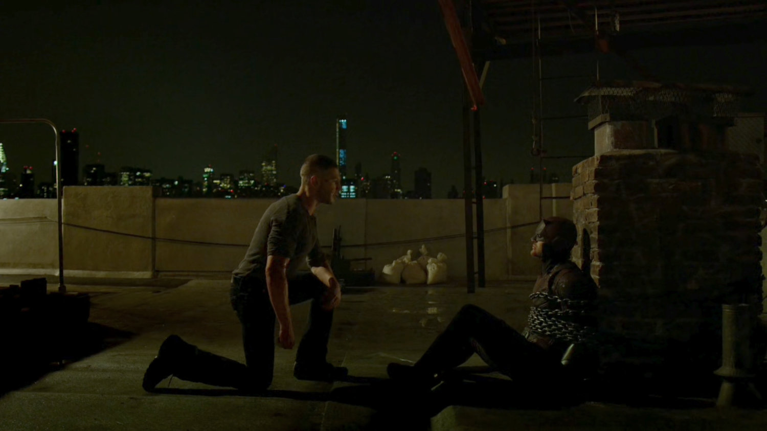 Frank with a chained up Daredevil on rooftop.