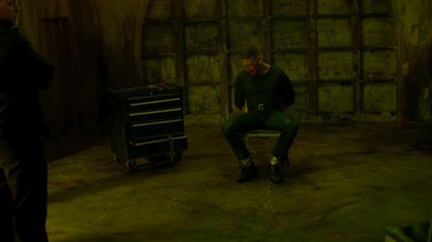 Frank tied to a chair in catacombs.