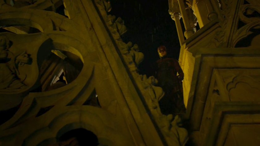 Daredevil standing in architecture above gates for St. Michael's Cemetery.