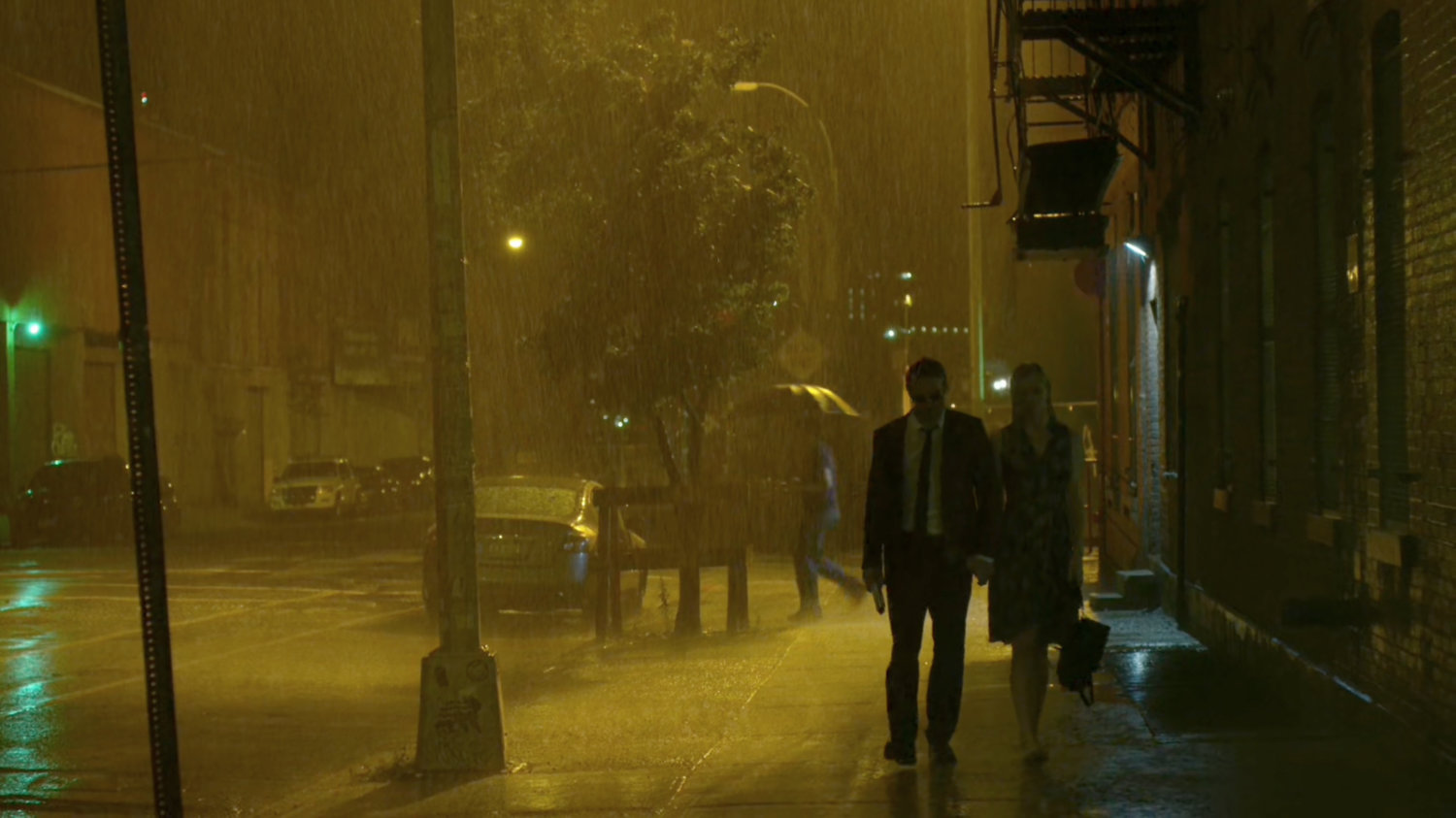 Matt and Karen walking along sidewalk in rain, outside Matt's apartment.