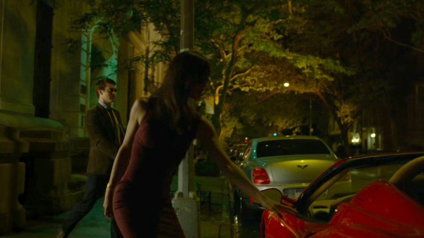 Elektra gets into a red sports car parked on the street outside faculty party.