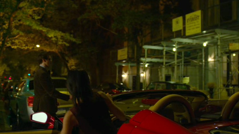 Elektra gets into a red sports car parked on the street outside faculty party.