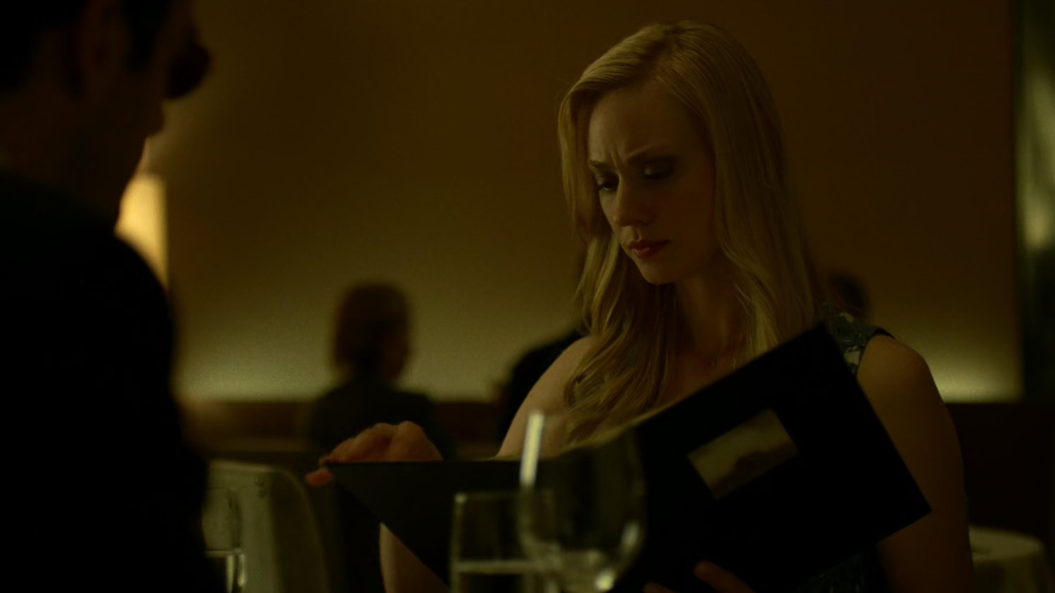 Karen reading a menu at a fancy restaurant.