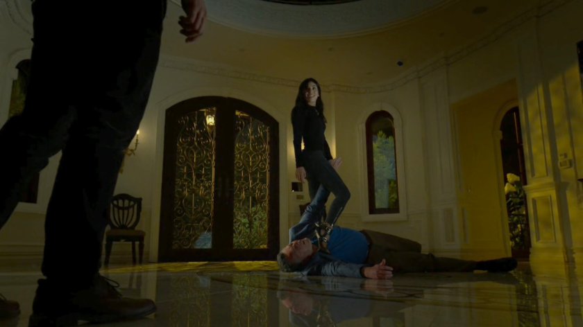 Elektra standing on Roscoe Sweeney's throat in the entryway to his mansion.