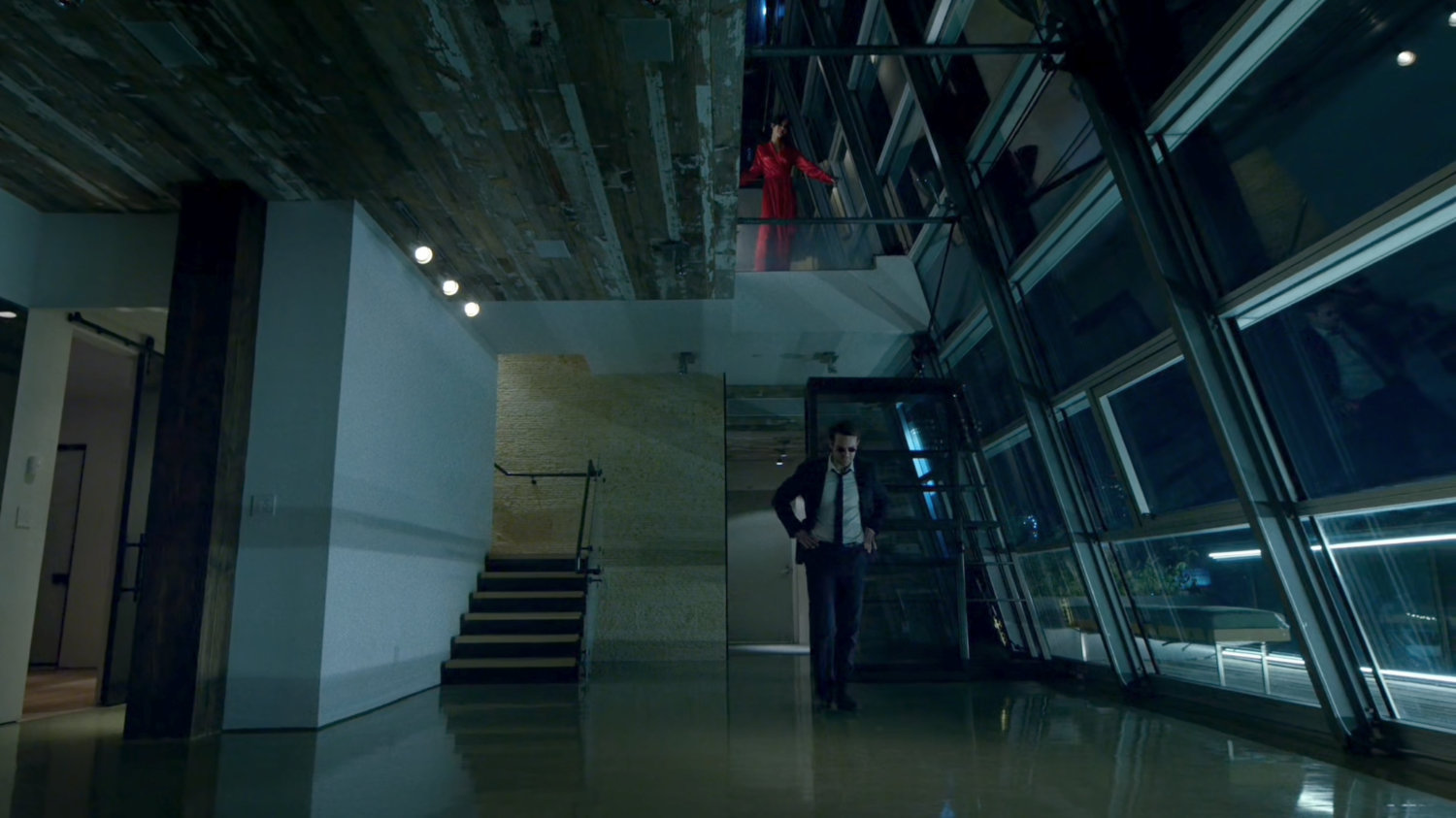 Matt enters Elektra's penthouse, while she looks down at him from the level above.