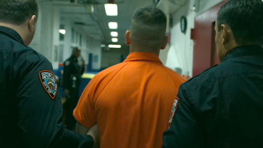 Frank Castle being escorted by two guards through prison hallway.