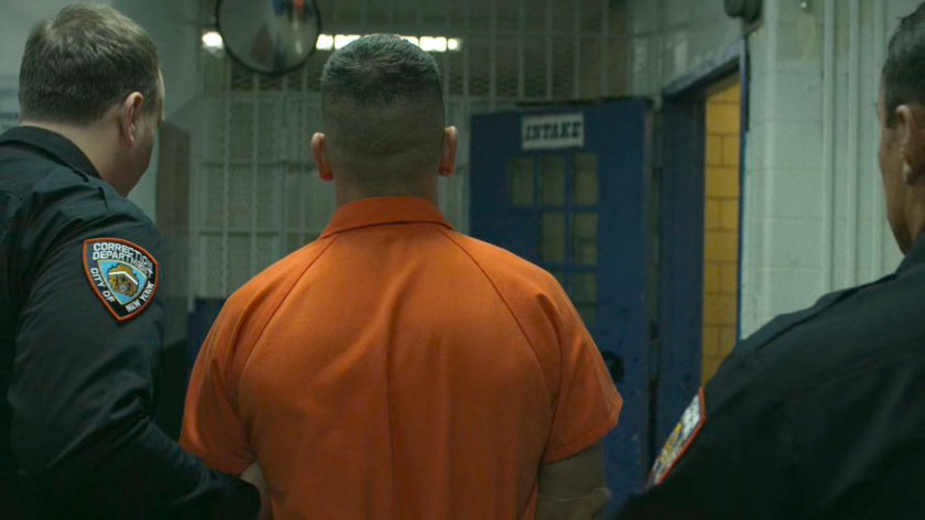 Frank Castle being escorted by two guards through prison hallway.