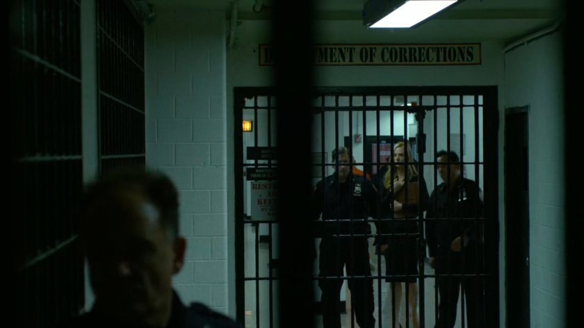 Karen being escorted through prison hallway.