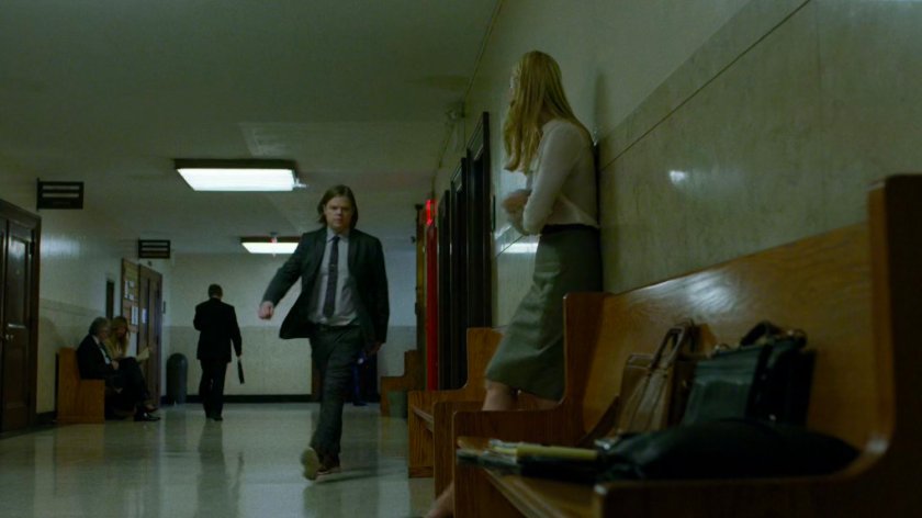 Foggy walks towards Karen in courthouse hallway.