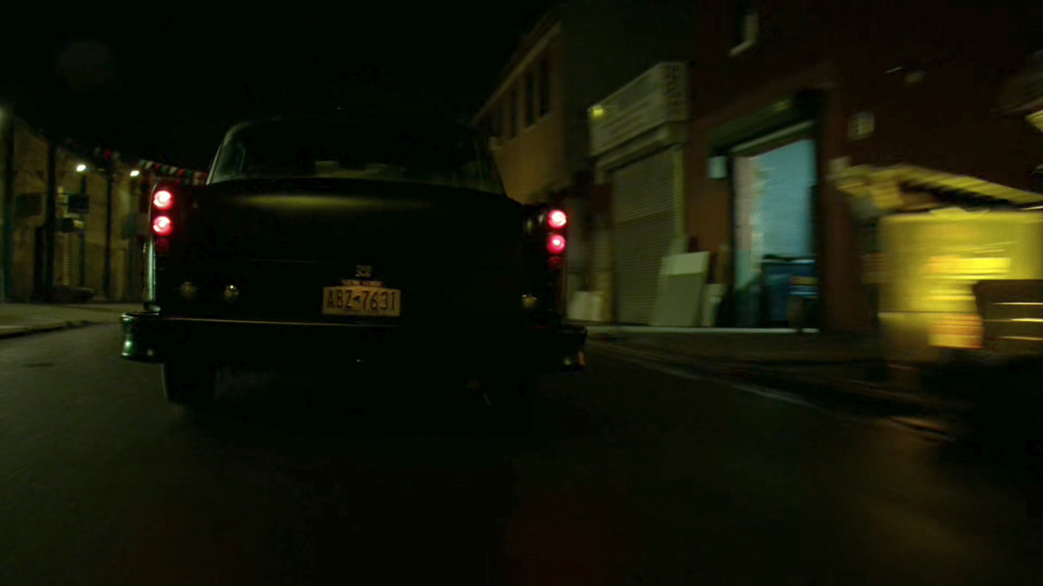 Stick's car drive down a narrow street at night.