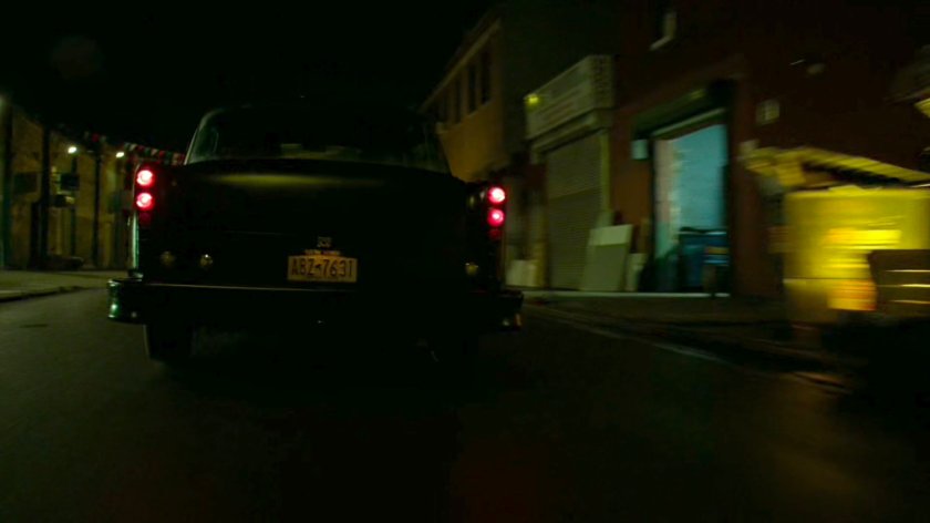 Stick's car drive down a narrow street at night.