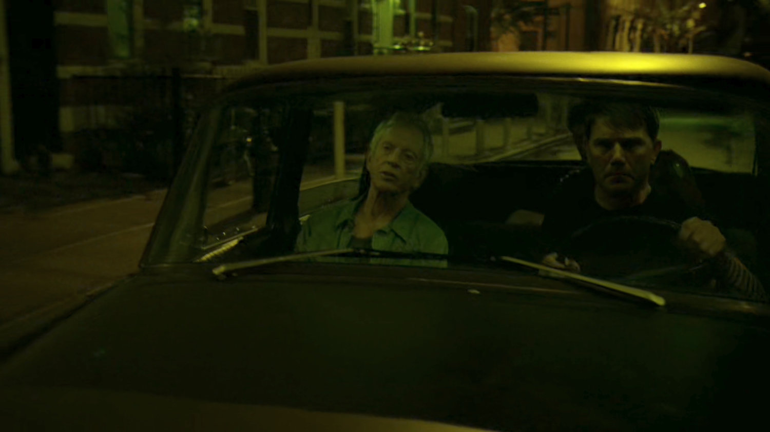 Stick and his driver in a car at night.