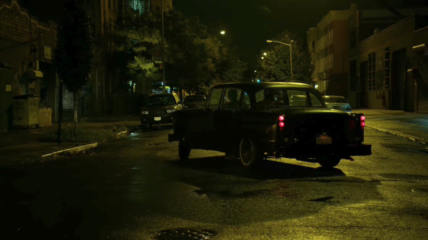 Stick's car drive down a narrow street at night.