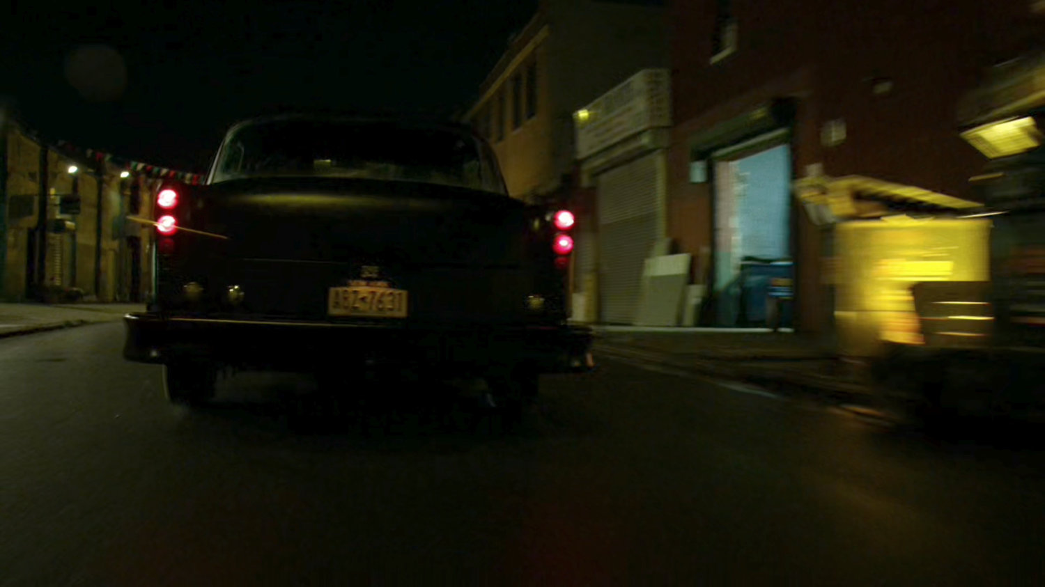Stick's car drive down a narrow street at night.