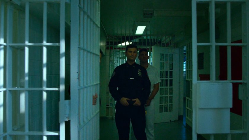 Frank and guard walking through Ryker's Island correctional facility.