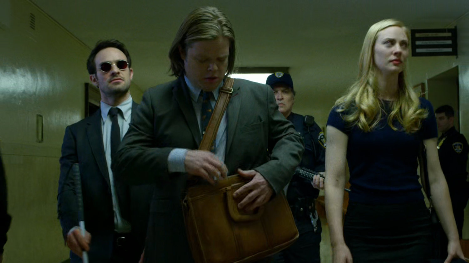 Matt, Karen, and Foggy led by police down a hallway in the courthouse.