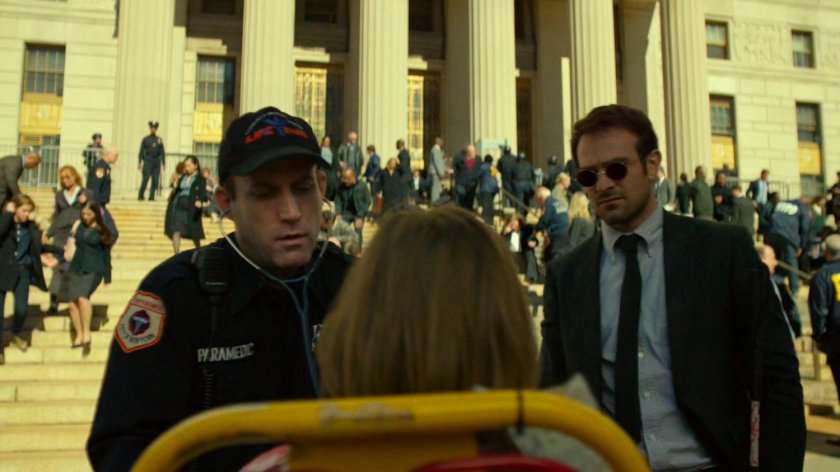 A paramedic examines Foggy outside the courthouse while Matt stands by.