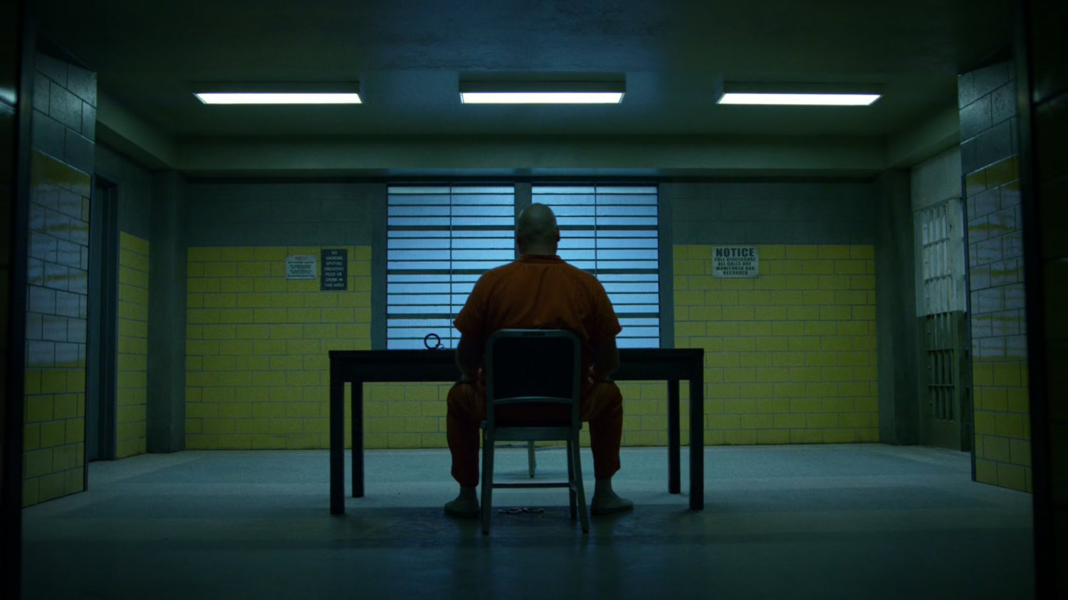 Wilson Fisk sitting at a table inside Ryker's Island correctional facility.