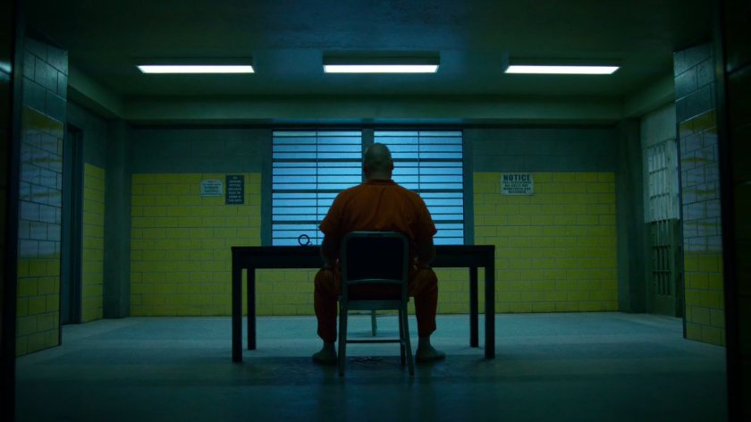 Wilson Fisk sitting at a table inside Ryker's Island correctional facility.