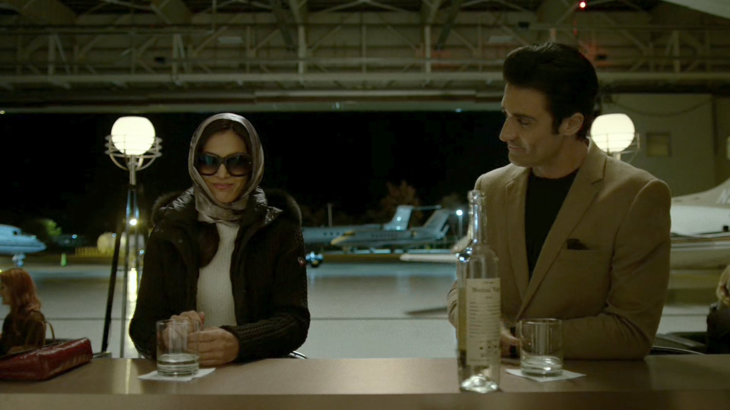 Elektra sitting with Jacques in a private airplane hangar.