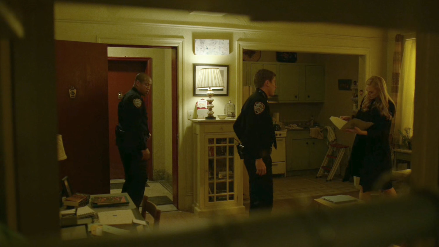 Officers check inside of Karen's apartment while she searches for paperwork.