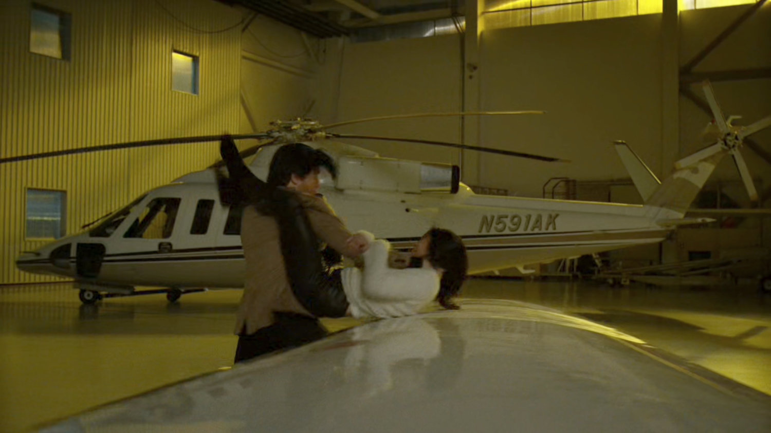 Elektra fighting with Jacques in a private airplane hangar.