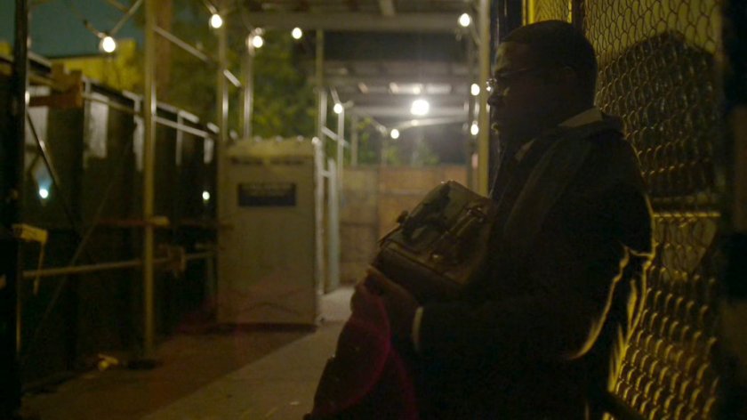 ADA Tower leaning against a chain link fence by a construction scaffolding.