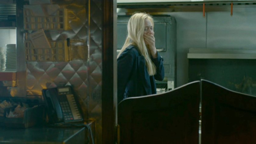 Karen covers her mouth in a diner kitchen.