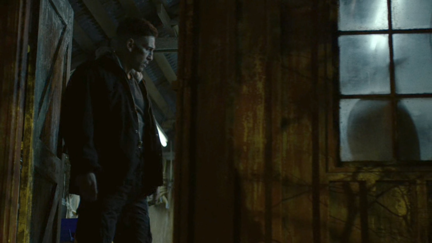 Frank standing in the doorway of a tool shed in the dark woods.