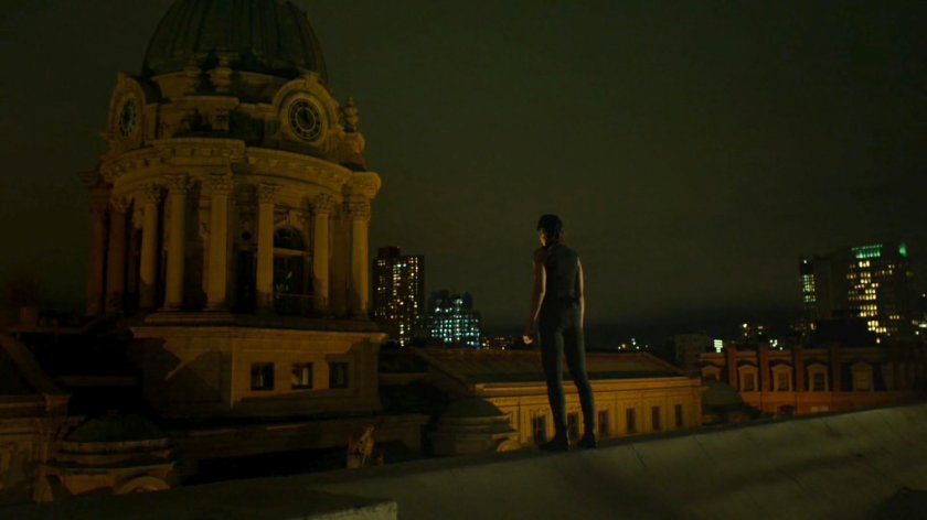 Elektra standing on the roof of Matt's apartment building, overlooking the city.