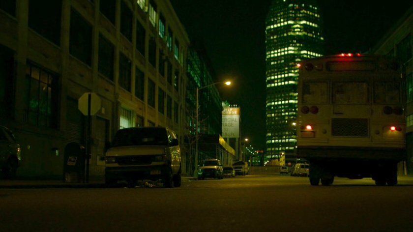 A bus belonging to The Hand drive along a dark street.